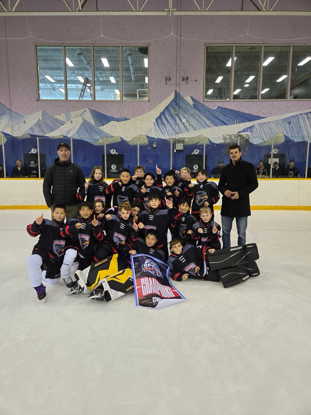 The Falcons pose with the Champions banner on the ice after winning gold at the BC Spring Classic
